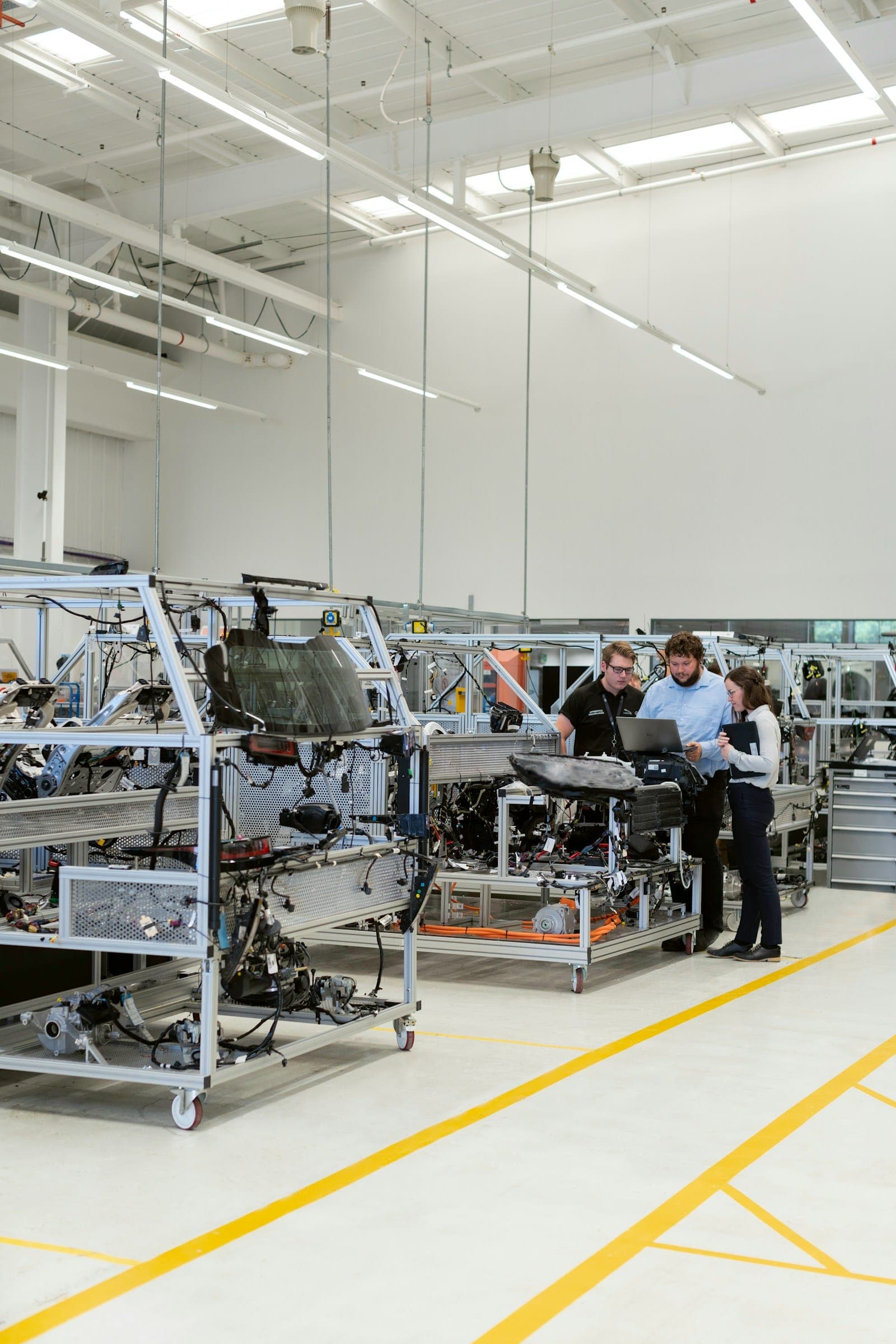 Engineers reviewing a laptop beside machinery on a factory floor